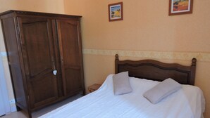 Una camera da letto con un armadio in legno, un letto con biancheria bianca e due quadri appesi al muro.