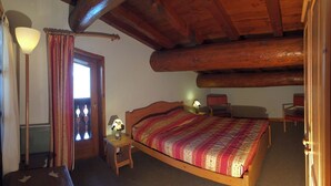 Une chambre confortable avec un lit en bois, une table de chevet avec une lampe, une fenêtre avec des rideaux et un plafond en bois.