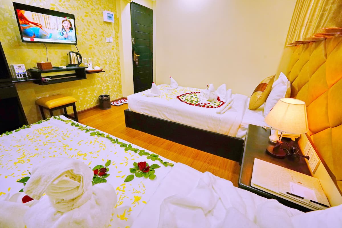 Une chambre d’hôtel avec deux lits, une télévision, un bureau et une lampe de chevet.