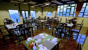 A restaurant with multiple tables set for dining, featuring a marble floor and large windows offering a view. - Royal Ruby Hotel (Mandalay)