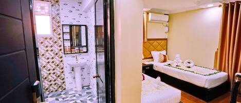 A hotel room with a tiled floor, a bed with a white bedspread, a bedside table, and a wall-mounted air conditioning unit.