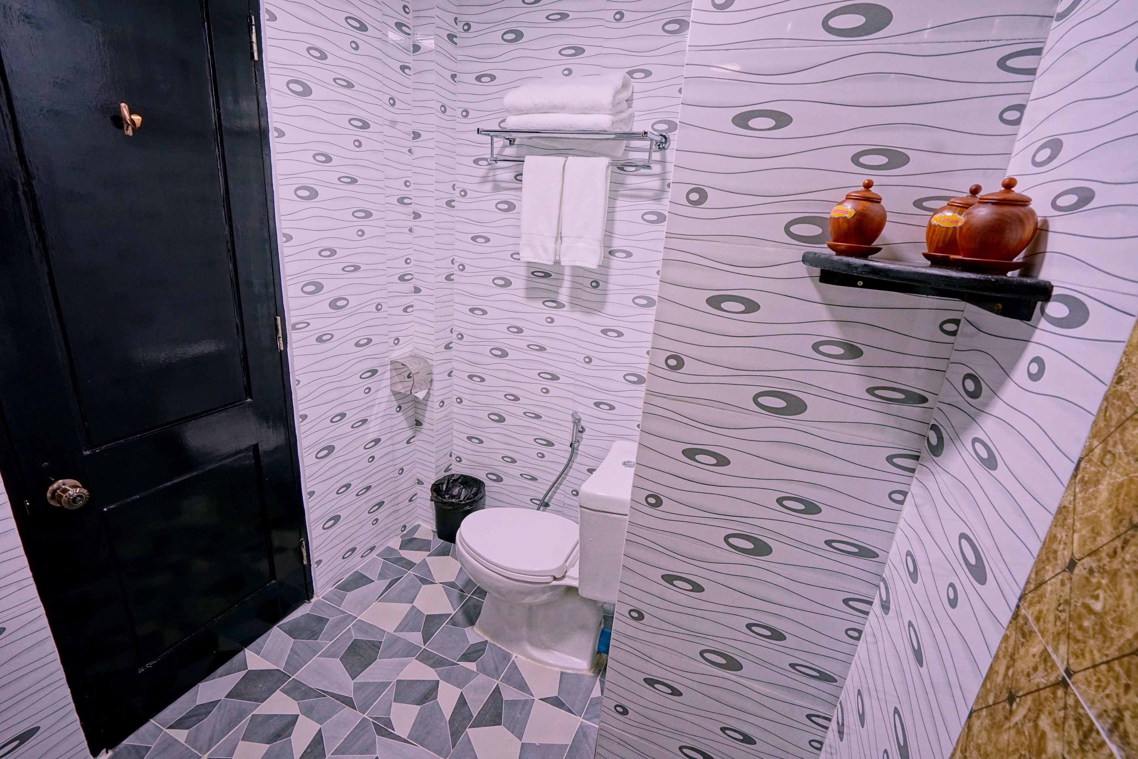 A bathroom with a toilet, a towel rack, and a shelf with two ceramic containers.