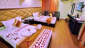 A hotel room with two beds, a desk, and a TV. - Royal Ruby Hotel (Mandalay)