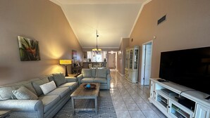 A living room with a sofa, coffee table, and TV stand. - Second Story Garden unit, Sleeps 6! (Sarasota)