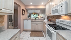 A modern kitchen with white cabinets, a built-in dishwasher, a microwave, and a stove. - Second Story Garden unit, Sleeps 6! (Sarasota)