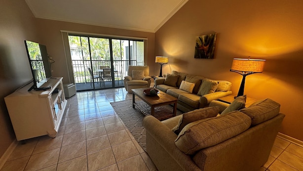 A living room with a sofa set, a coffee table, a TV, and a lamp. - Second Story Garden unit, Sleeps 6! (Sarasota)