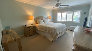 A bedroom with a bed, two bedside tables with lamps, a ceiling fan, and a window with blinds. - Second Story Garden unit, Sleeps 6! (Sarasota)