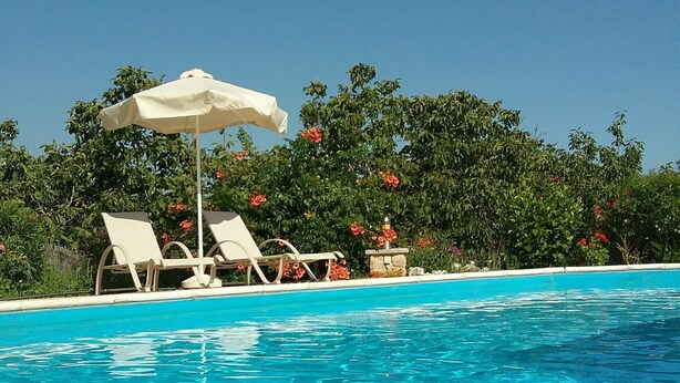 A clear blue pool with lounge chairs and an umbrella. - Villa Koumneni - Sea and mountain peace and tranquility (Paphos)