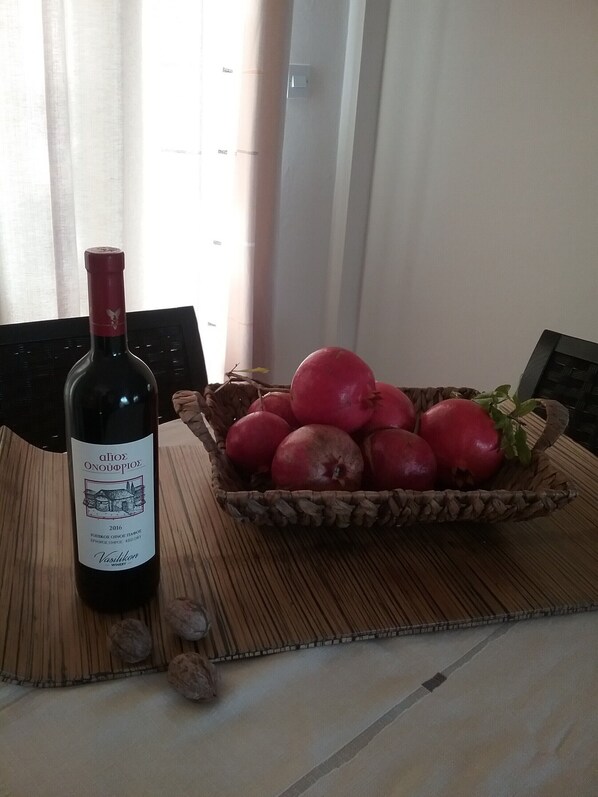 Une bouteille de vin et un panier de grenades sur une table.