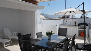 A rooftop terrace with a dining table, chairs, and umbrellas. - AP290 - Casa Olivia (Nerja)
