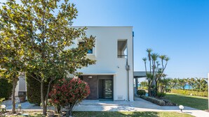 A modern two-story house with a flat roof, a front door, and a small porch area.