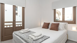 Ein Schlafzimmer mit einem Bett, zwei Fenstern und einer Tür.