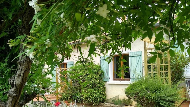 A rustic house with a garden, a wooden fence, and a small pond.