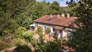 A house with a tiled roof, solar panels, and a garden with a pergola.