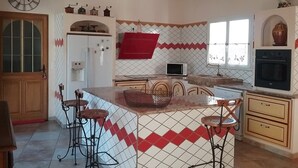 A kitchen with a central island, bar stools, a microwave, and a stove.