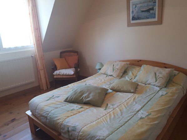 A bedroom with a wooden bed, a chair, a lamp, and a painting on the wall. - Charming house in Locquirec (Locquirec)