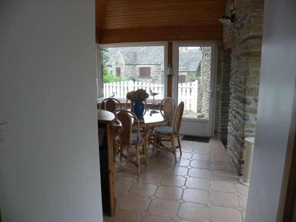 A dining area with a table and chairs, a view of the outside, and a stone wall.