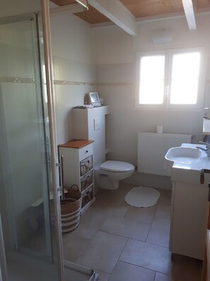A small bathroom with a toilet, sink, and shower.