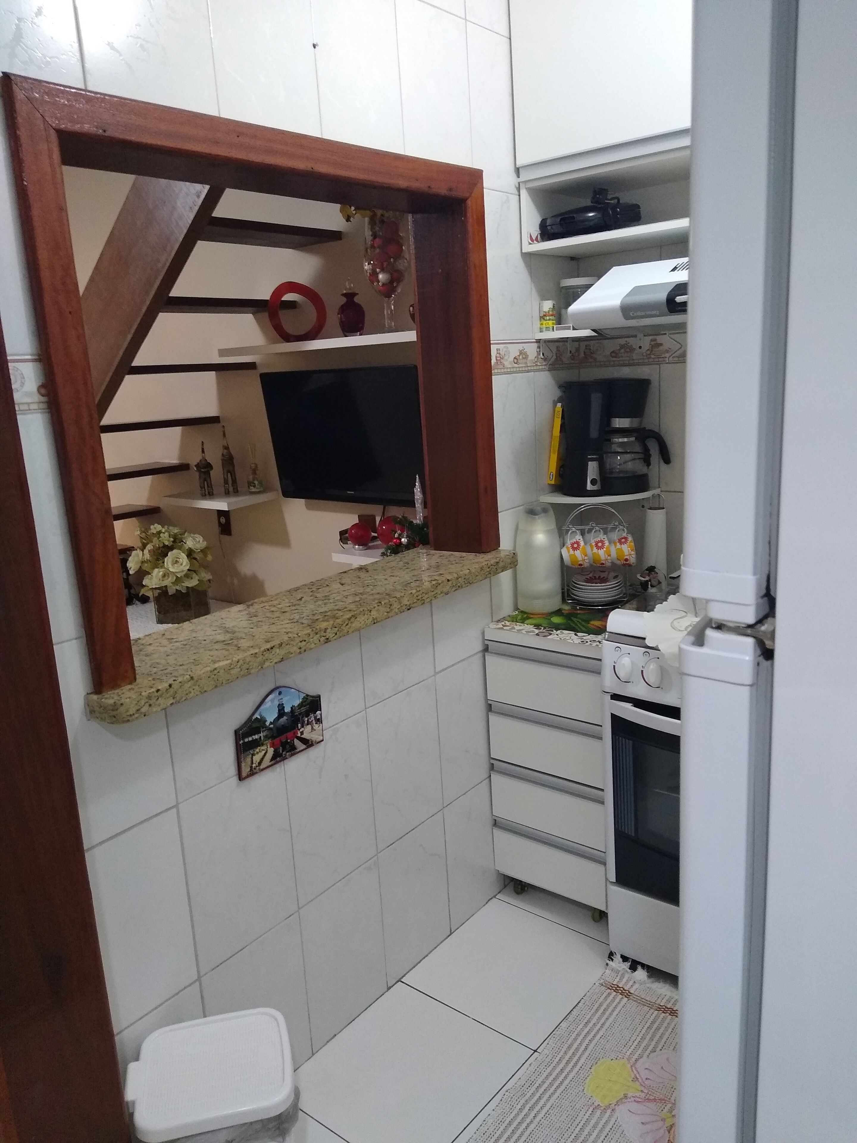 A compact kitchen with a built-in TV, a coffee maker, and a microwave.
