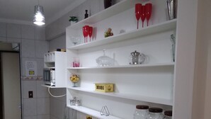 Una cocina con gabinetes blancos, microondas, refrigerador y un comedor con mesa y sillas blancas.