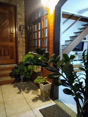 A staircase leading to a landing with a wooden door and a stone wall. - Cozy house in the center of Armação dos Búzios  (Armação dos Búzios)