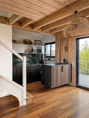 Una cocina moderna con vigas de madera, encimera negra y una lámpara colgante.