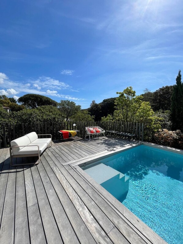 A wooden deck with a pool, a white sofa, and a red chair. - House Porto Vecchio 8 pers. with pool can be heatable  (Porto-Vecchio)