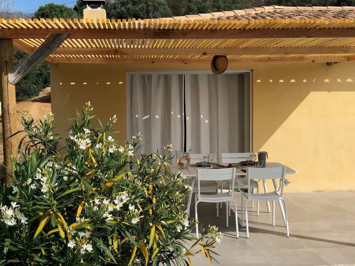 Une terrasse extérieure avec une table et des chaises, une pergola et une vue sur une montagne.