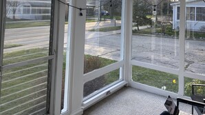 Et værelse med loftventilator, store vinduer og en person, der bruger en bærbar computer.