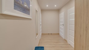 A hallway with wooden flooring, white doors, and a framed picture on the wall. - Dream Loft Krosna (Gdansk)