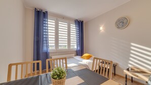 A room with a bed, a table with chairs, a window with curtains, and a wall-mounted light fixture. - Dream Loft Krosna (Gdansk)