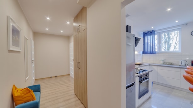 A modern apartment with a kitchenette, a dining area, and a living room with a blue sofa and a yellow pillow. - Dream Loft Krosna (Gdansk)