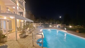 Une piscine entourée d’une terrasse dallée de pierres, agrémentée de plantes en pot et de mobilier d’extérieur.