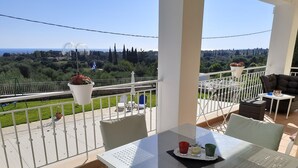Un balcon avec une table, des chaises et des plantes en pot.