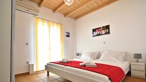 Une chambre à coucher avec un lit, une table de chevet, une lampe, un tableau au mur et une fenêtre avec des rideaux.