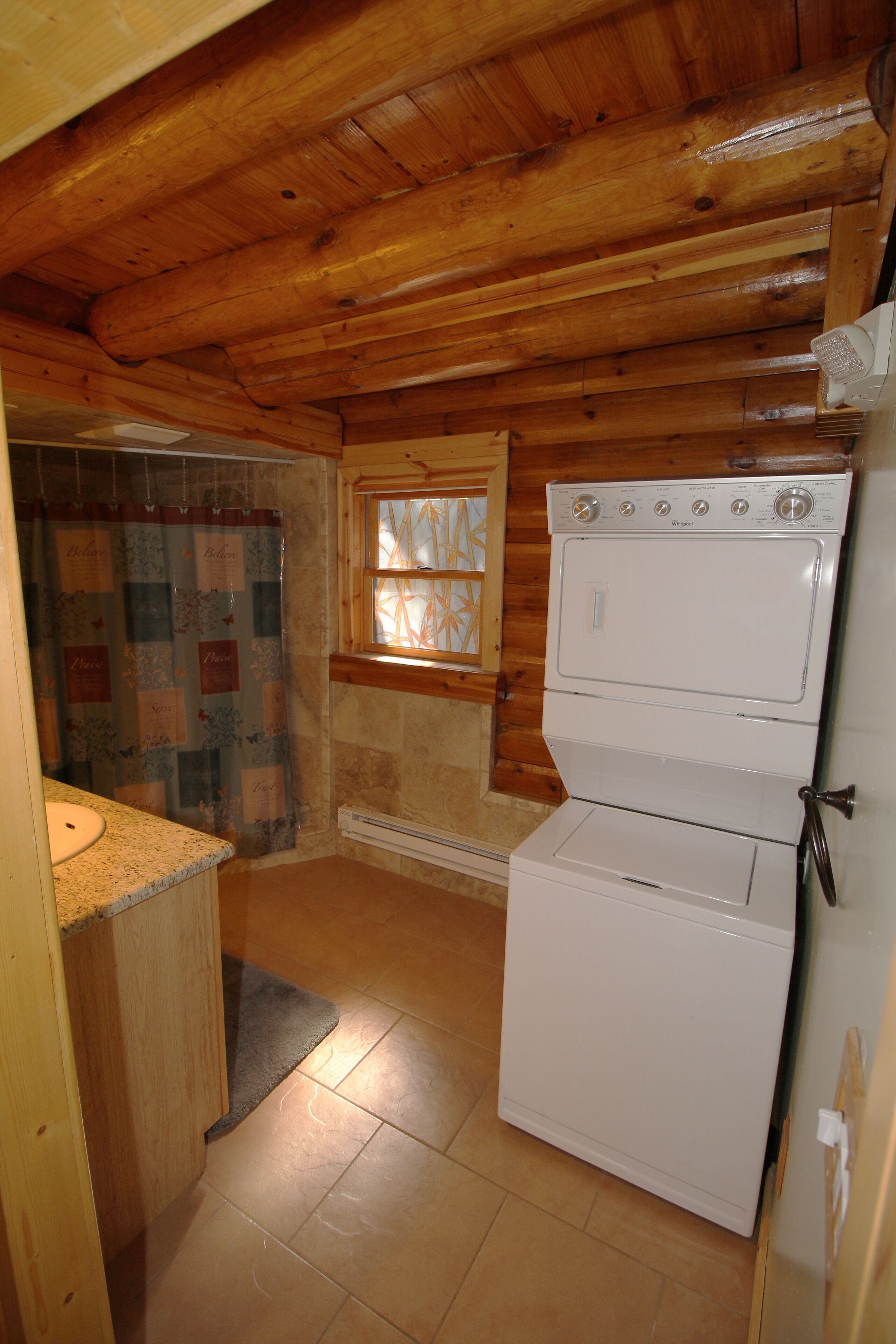 Una cucina compatta con pareti in legno, una finestra, un forno doppio e un lavello.