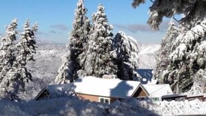 Et snøklædt landskab med en hytte og en vej.