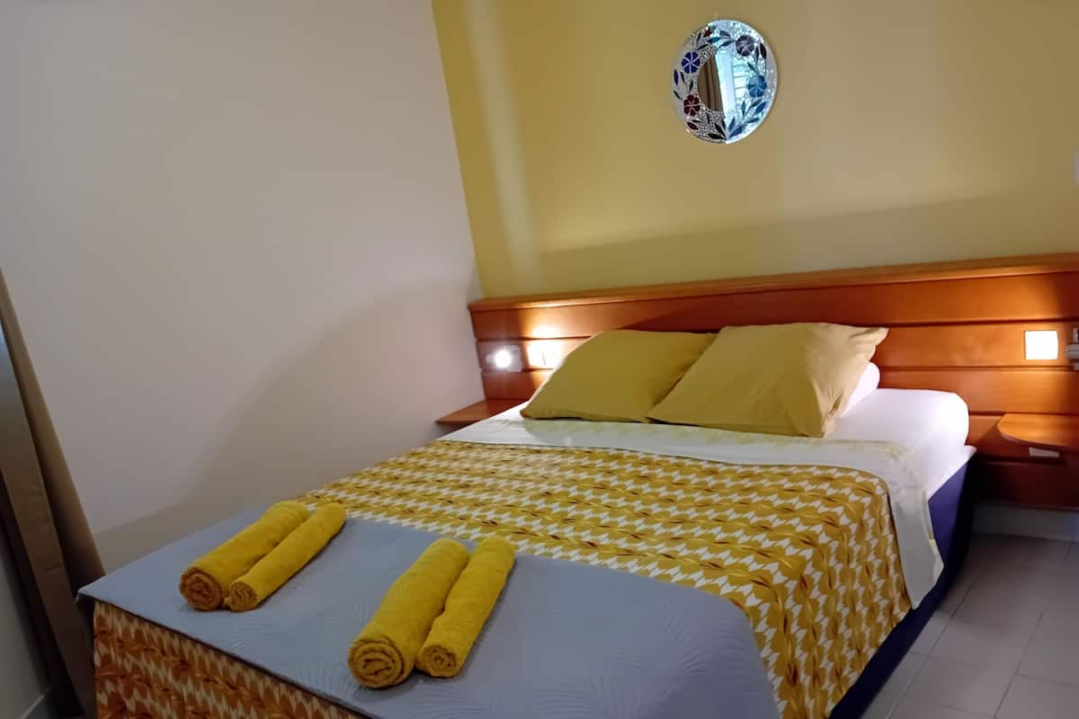 Une chambre d’hôtel avec un lit, une tête de lit, une table de chevet et un miroir fixé au mur.