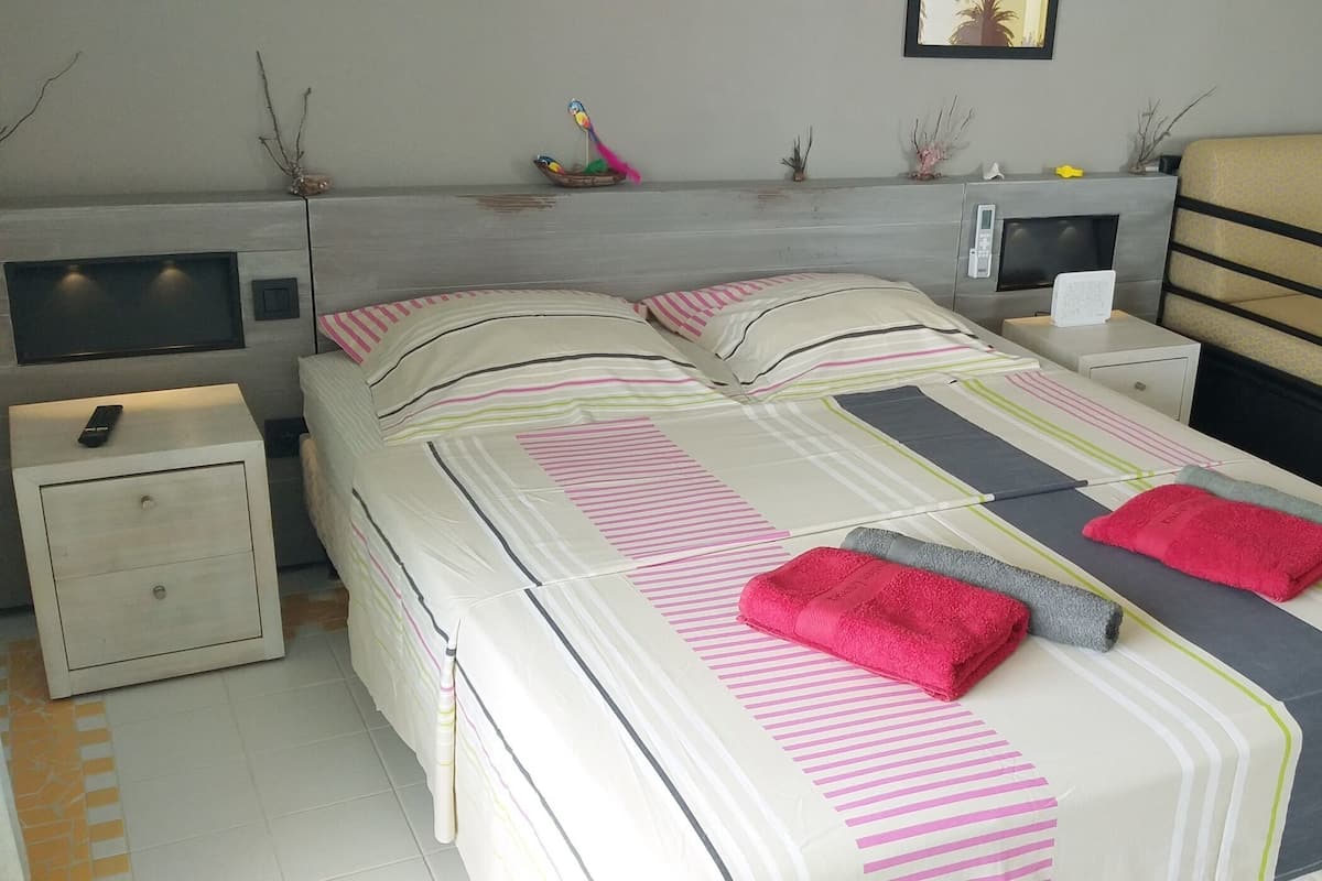Une chambre bien rangée, avec un lit, des tables de chevet, une télévision, un canapé et une petite table.