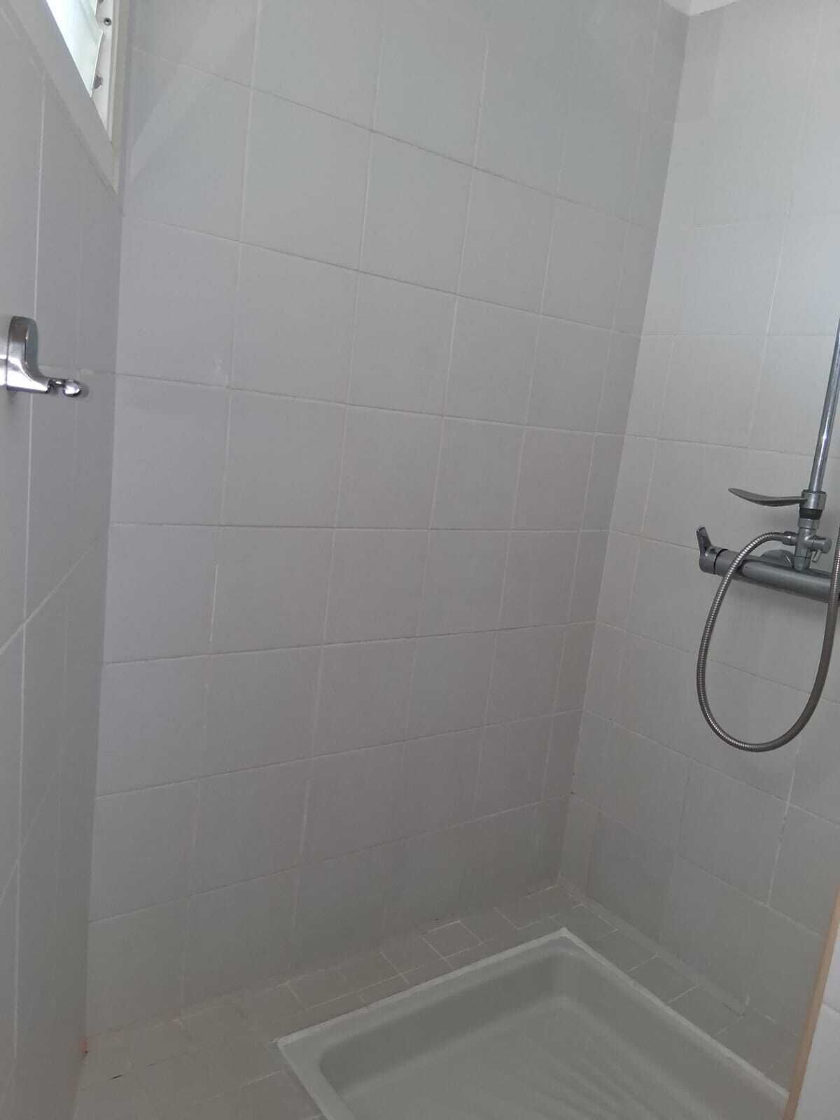 Un baño pequeño con azulejos, una ducha y un cabezal de ducha manual.