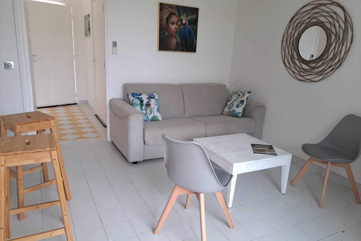 Un salon comprenant un canapé, une table basse, un fauteuil et un tabouret en bois.