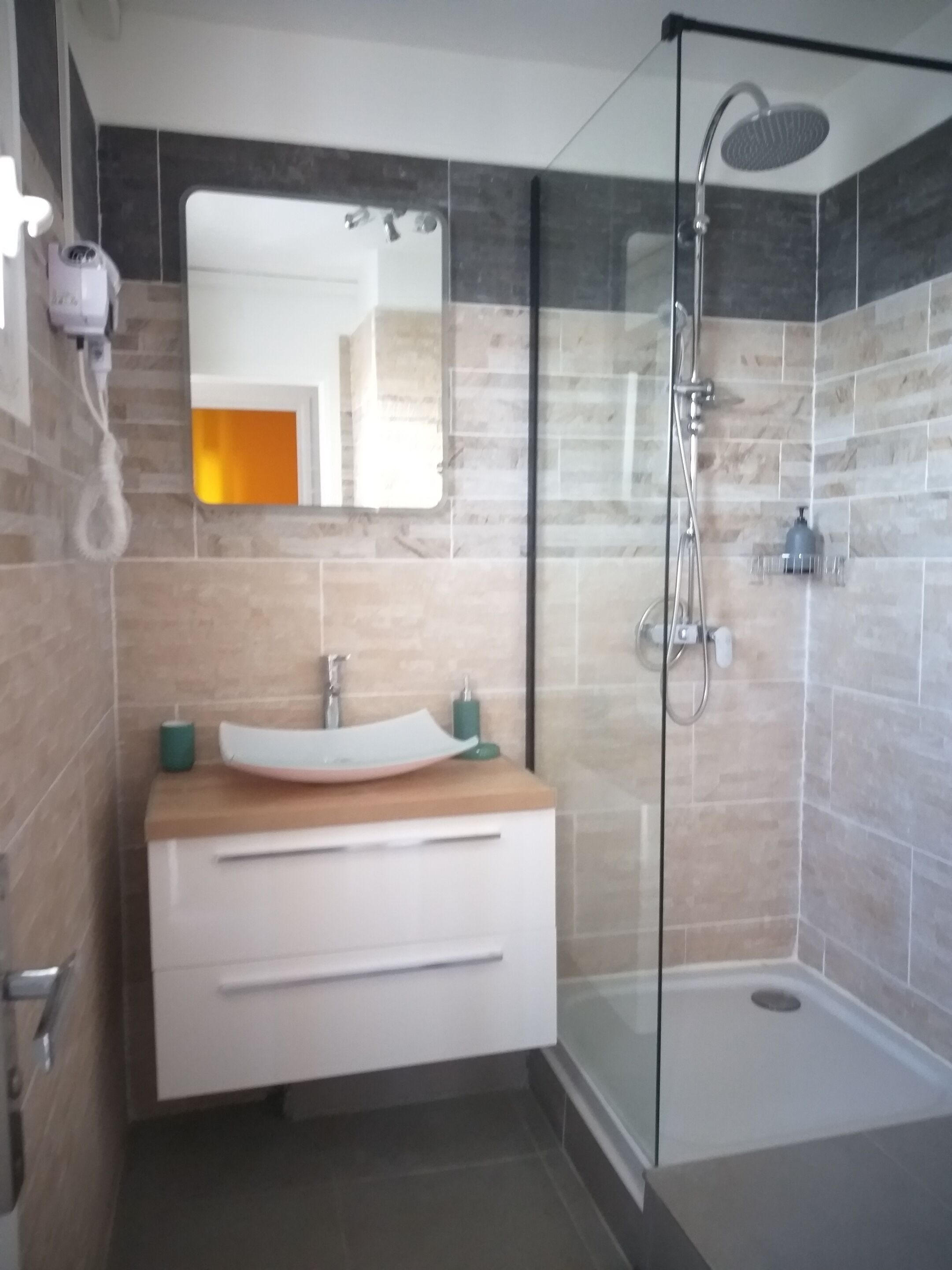 A modern bathroom with a glass-enclosed shower, a vanity with a sink, and a mirror.