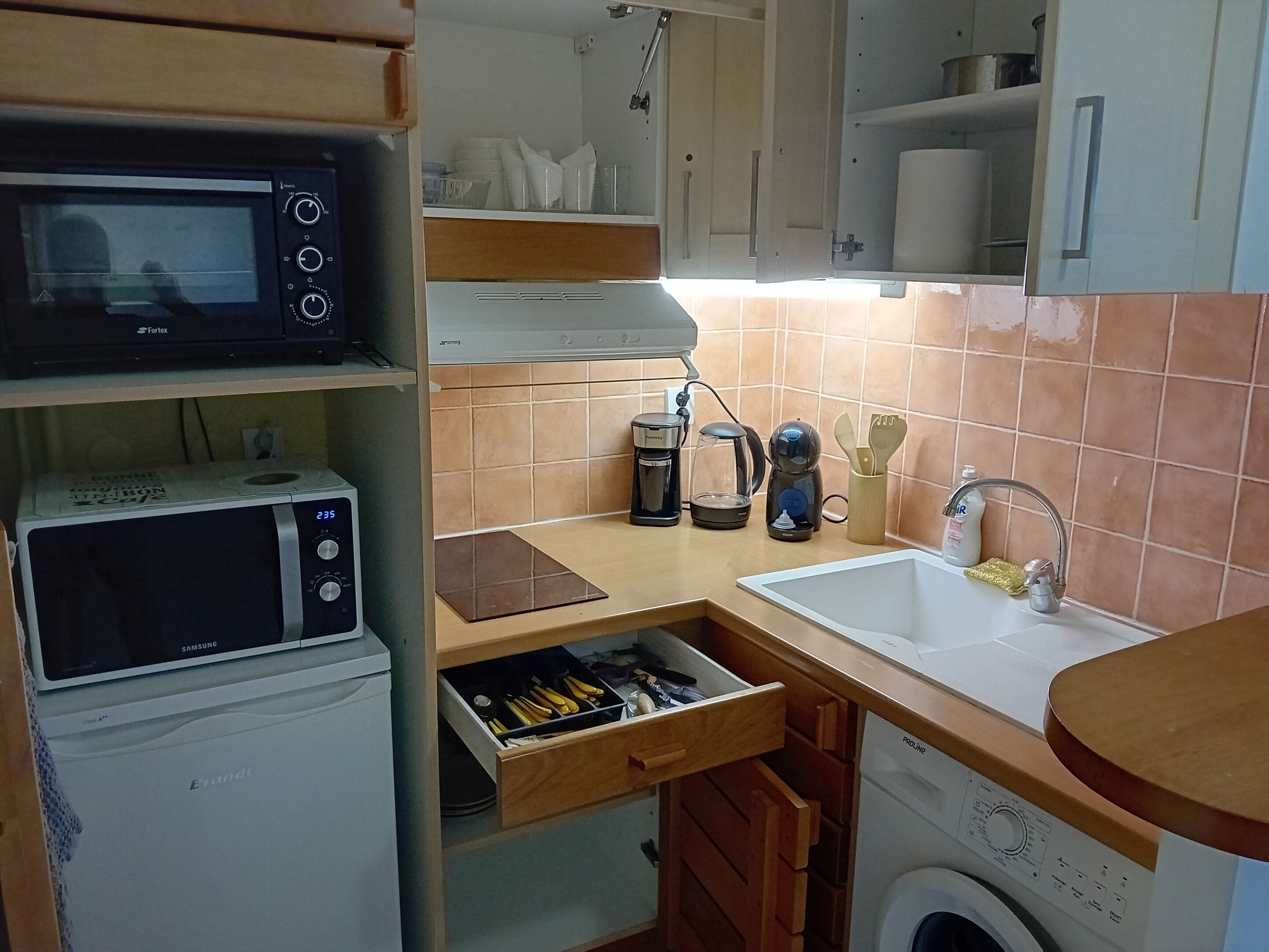 Eine kleine Küche mit Mikrowelle, Kaffeemaschine und Waschmaschine.