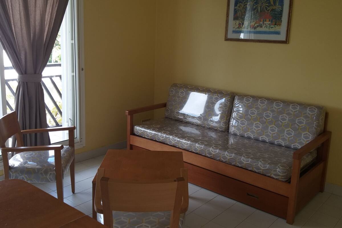 Une pièce comprenant un canapé en bois, une chaise en bois et une table.