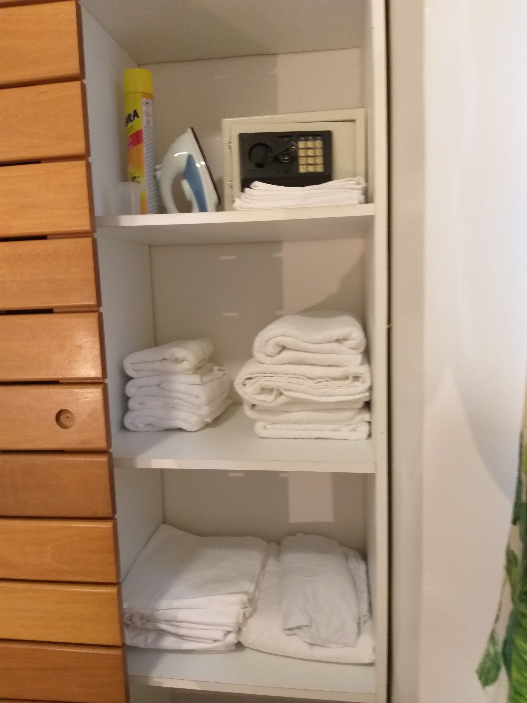 A white wardrobe with multiple shelves, each holding folded white towels.