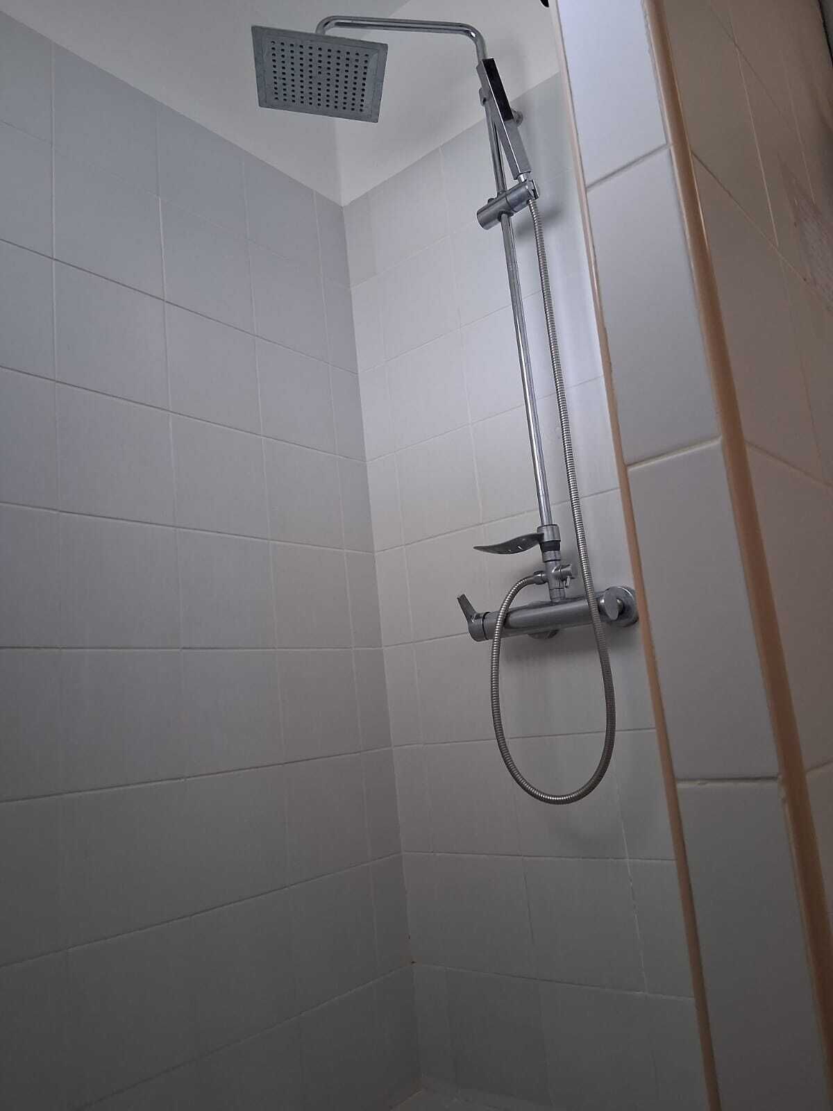 A shower area with a handheld showerhead and a fixed showerhead mounted on the wall.