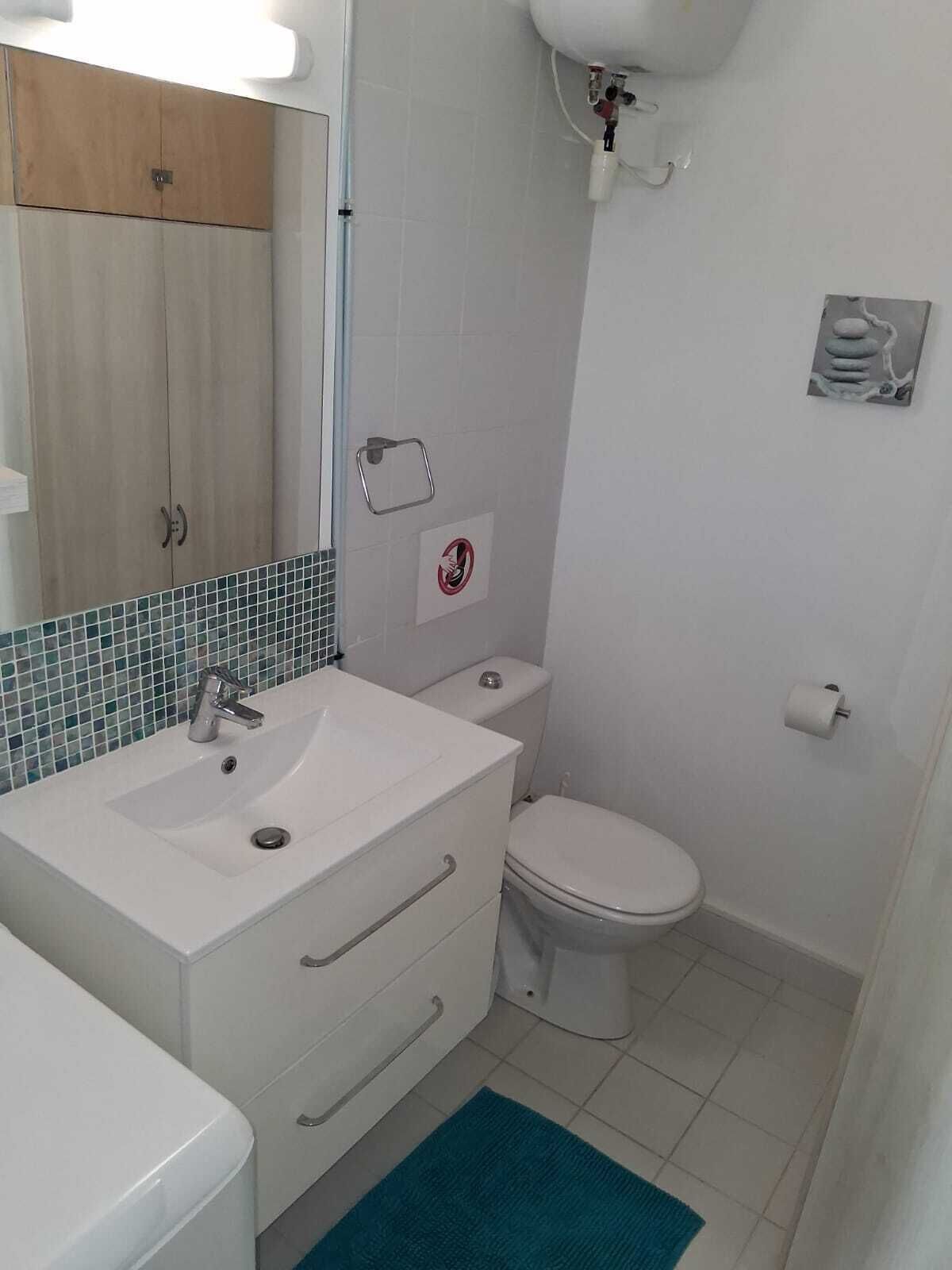 A bathroom with a white sink, mirror, toilet, and a towel rack.