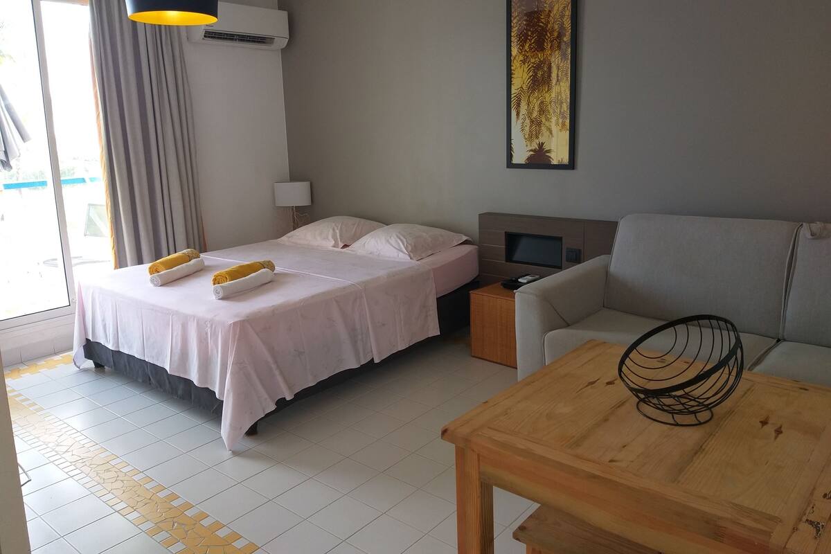 Une chambre d’hôtel avec un lit, un canapé, une table en bois, une télévision et un tableau au mur.