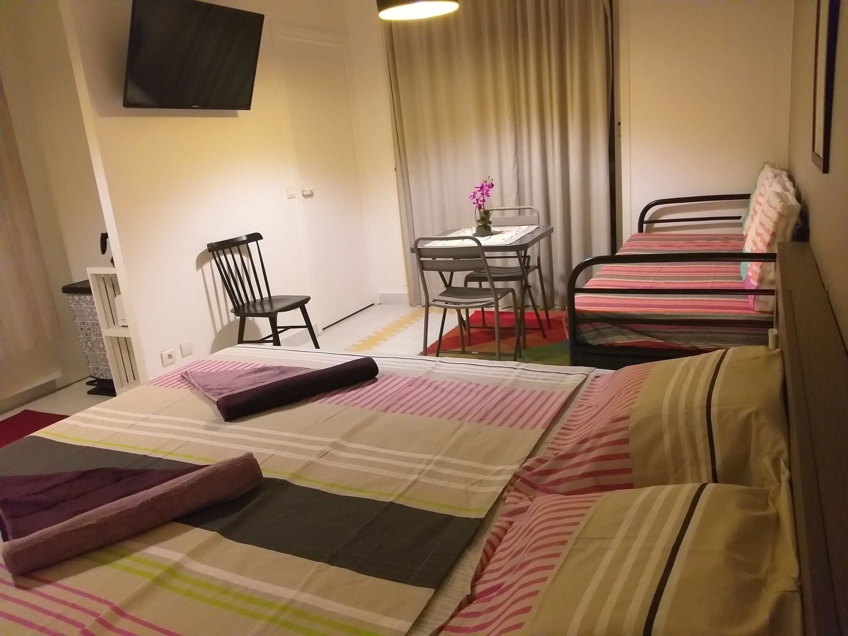 A hotel room with a bed, a desk, a chair, and a TV.
