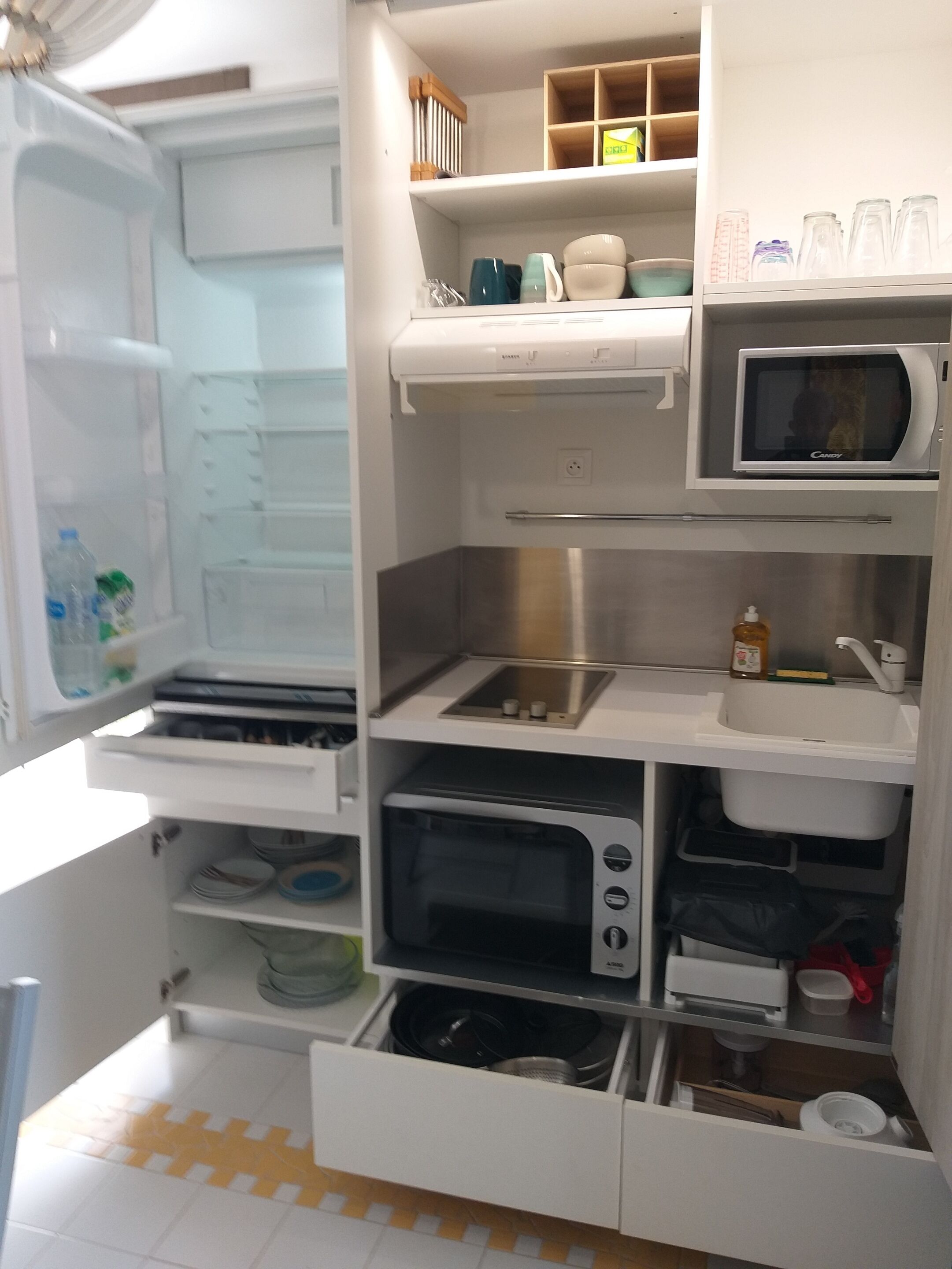Une cuisine compacte équipée d’un four à micro-ondes encastré, d’un grille-pain et d’un évier.